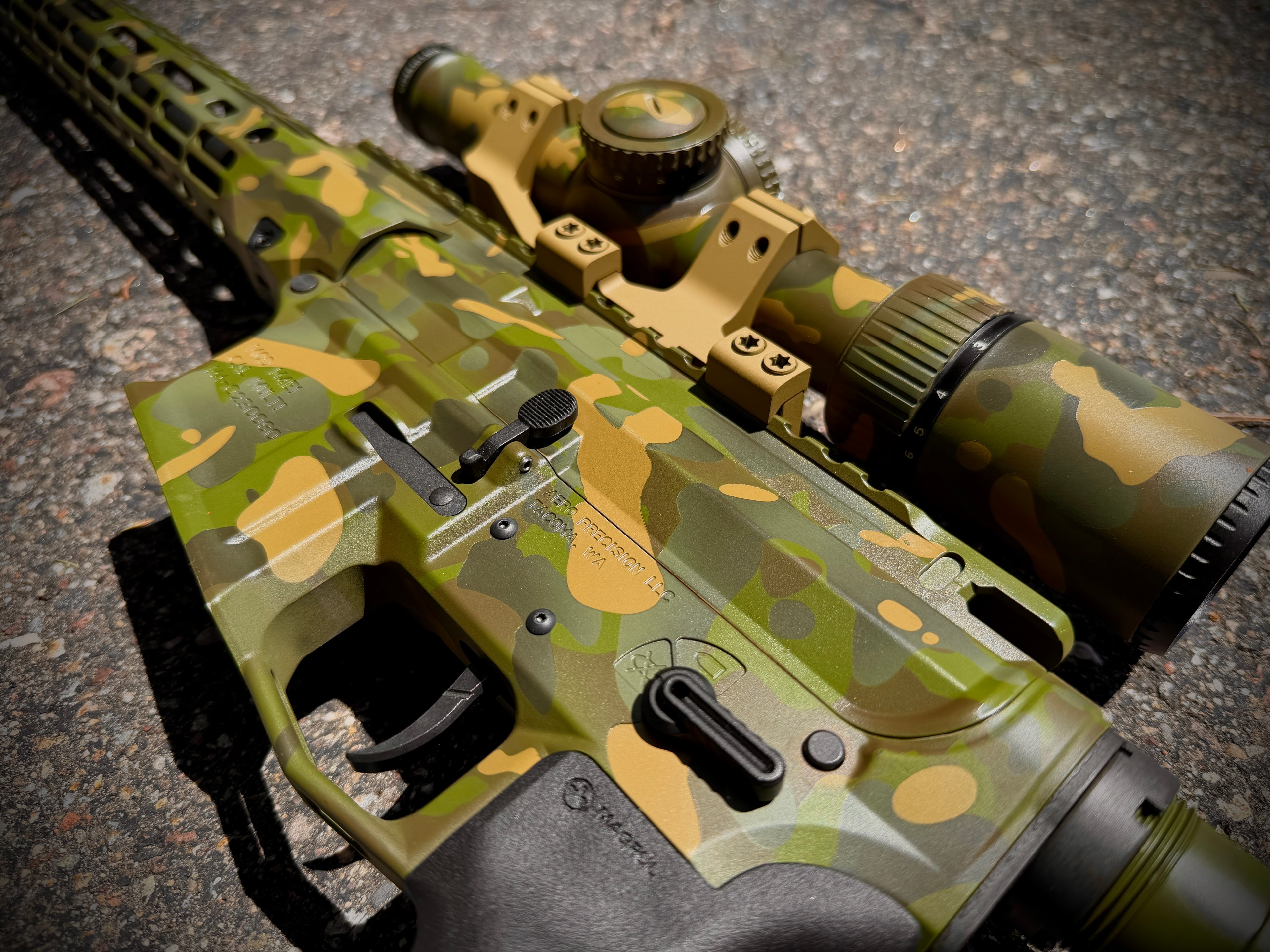 Full camo Cerakote Aero Precision rifle with matching scope rings and optic — green, tan, and black pattern photographed outdoors by Northwoods Firearms