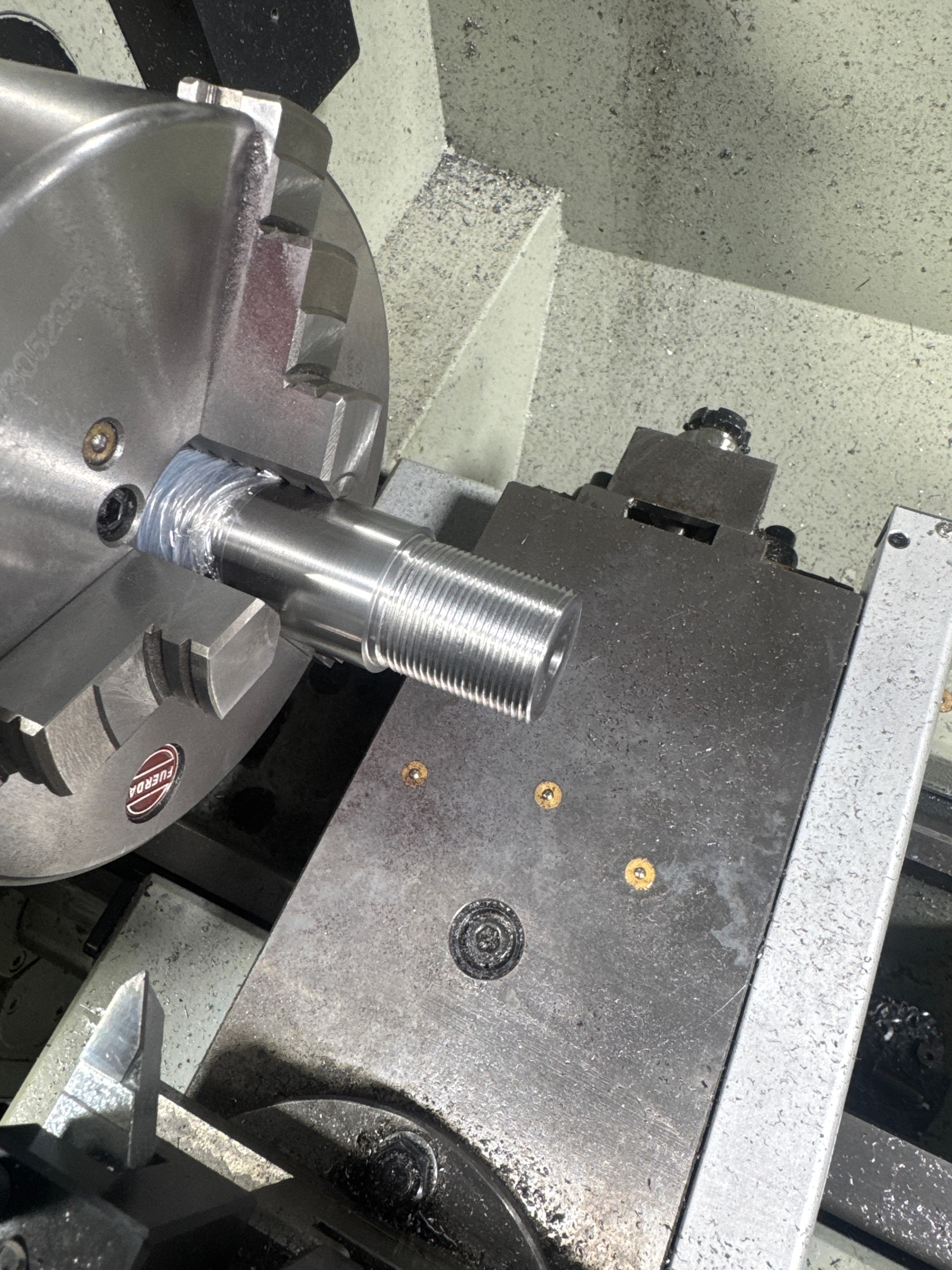 Threaded barrel muzzle held in Furron lathe chuck with threading tool engaged — barrel threading in progress at Northwoods Firearms, Crandon, WI