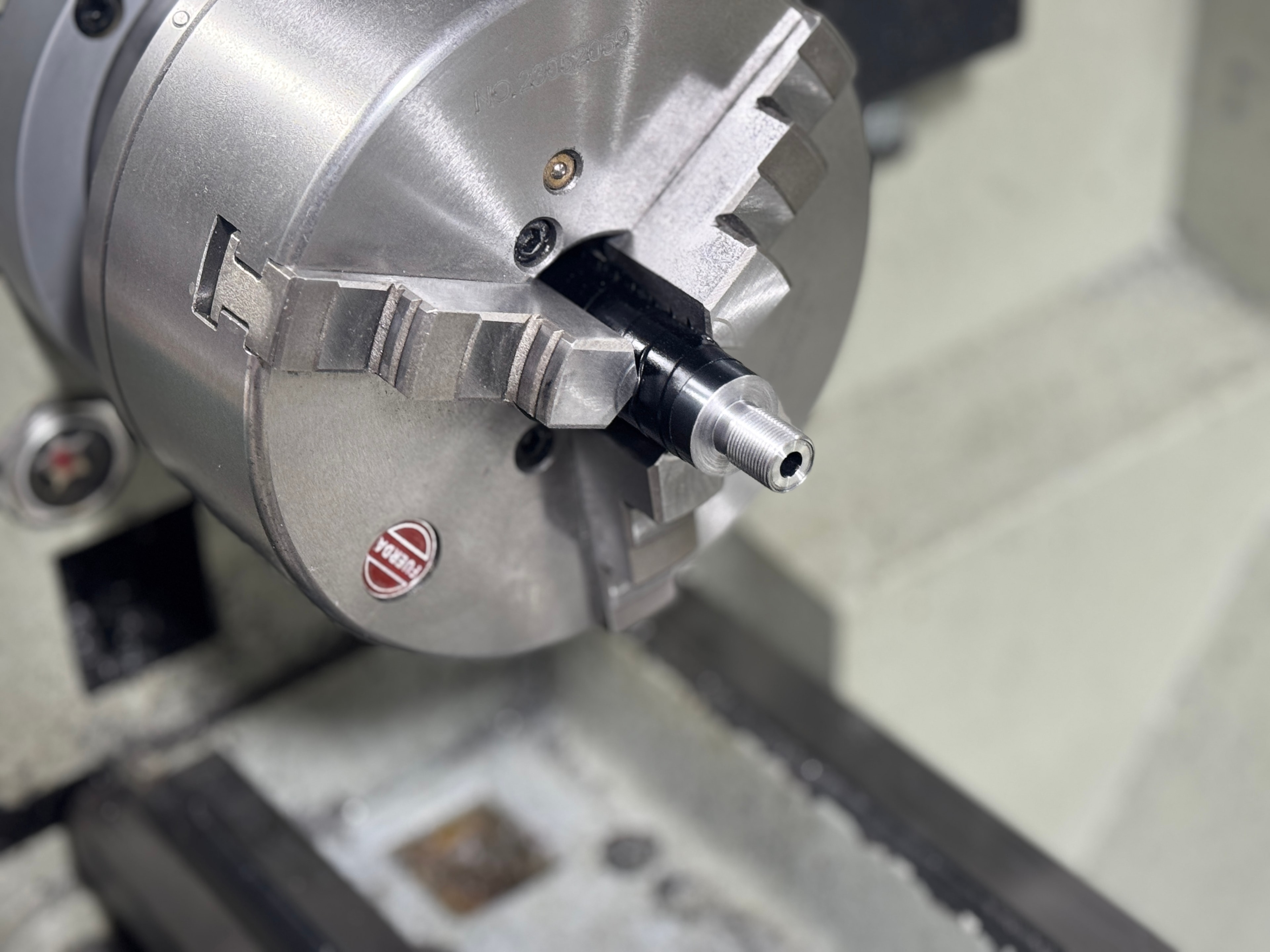 Close-up of a threaded barrel stub held in the Furron 3-jaw lathe chuck — barrel threading at Northwoods Firearms, Crandon, WI