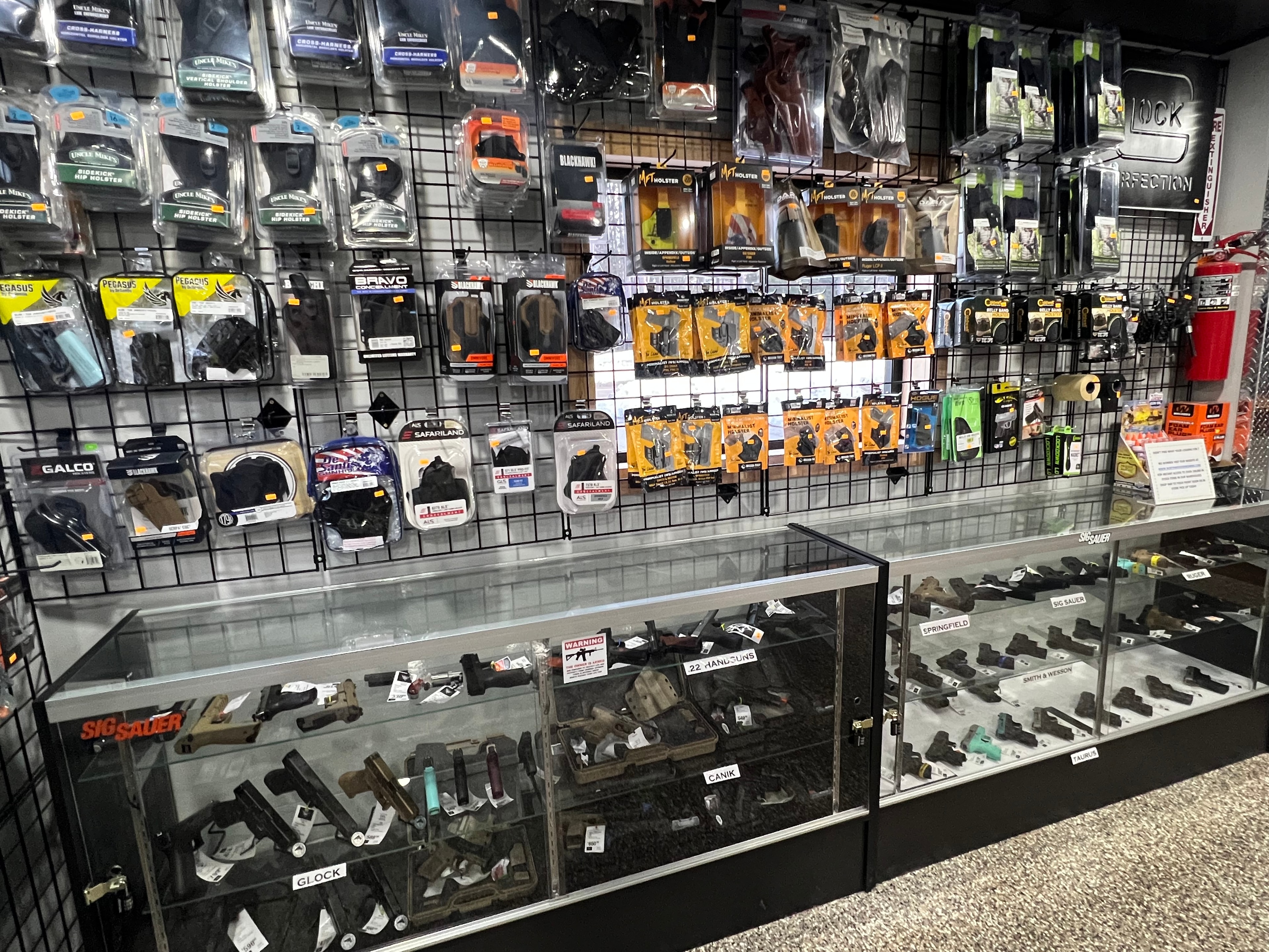 Northwoods Firearms handgun wall — Glock, Sig Sauer, Springfield, Smith & Wesson, Canik, and Taurus display cases with holster wall