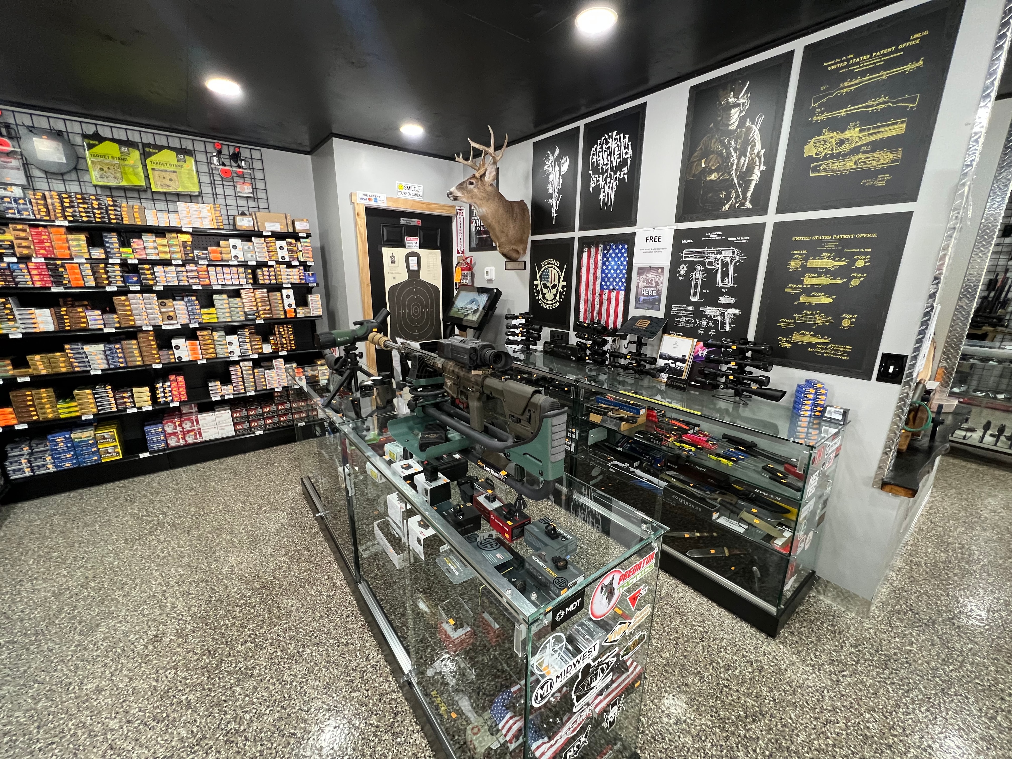 Northwoods Firearms rifle counter overview — precision rifles, scopes, ammo wall, and military art prints