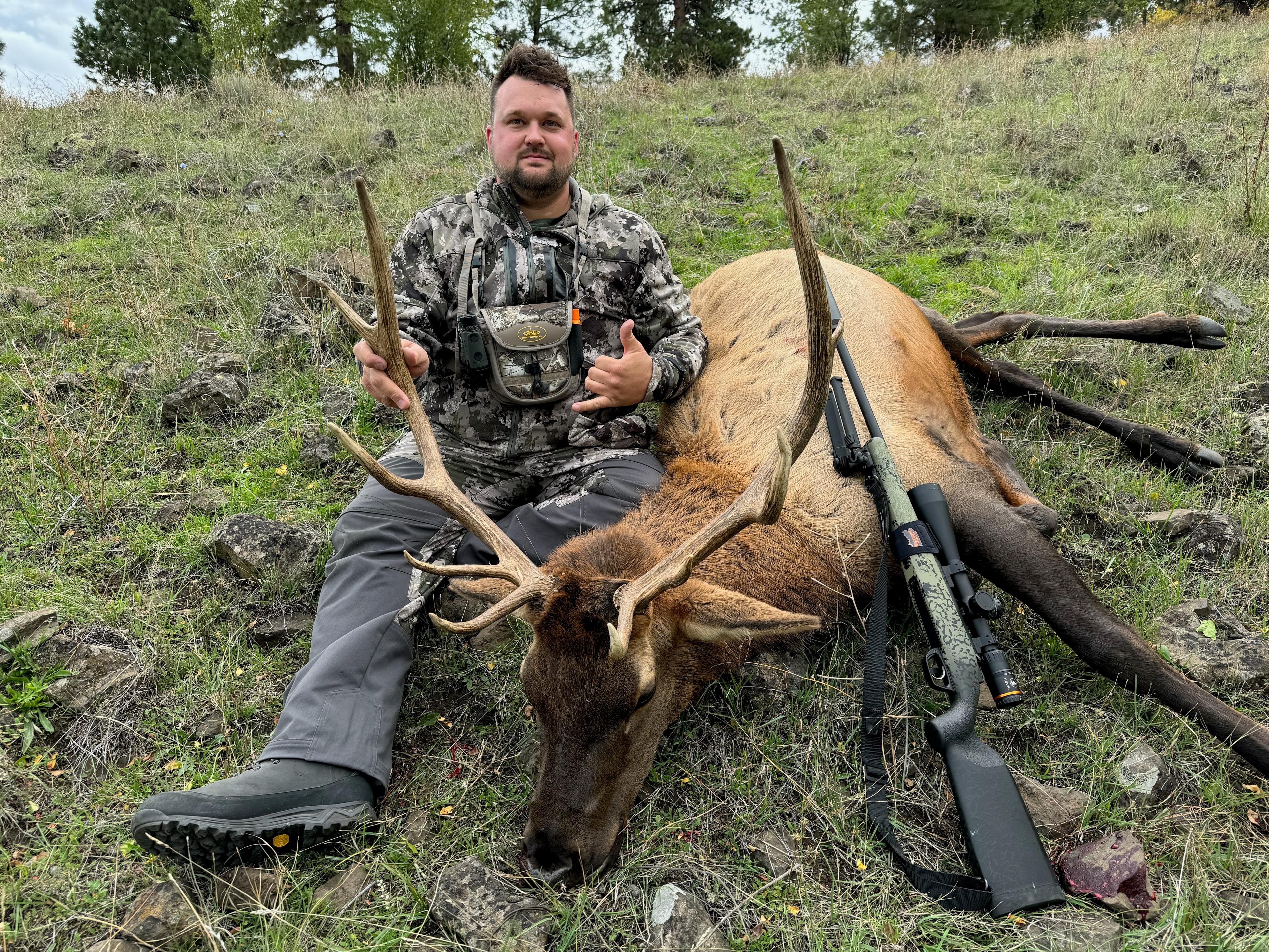 Hunter with bull elk and custom precision rifle, overhead perspective