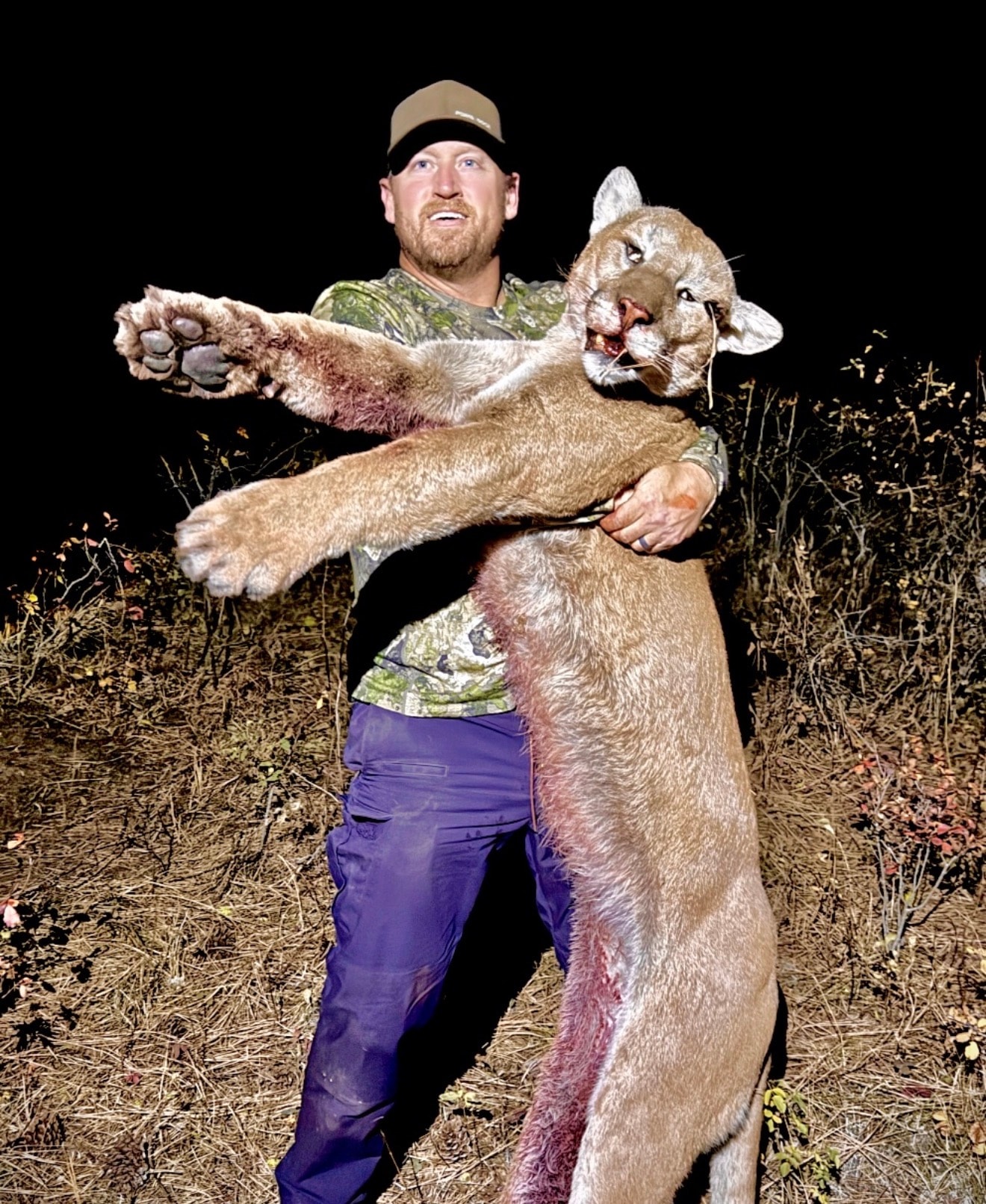 Hunter holding mountain lion harvest at night