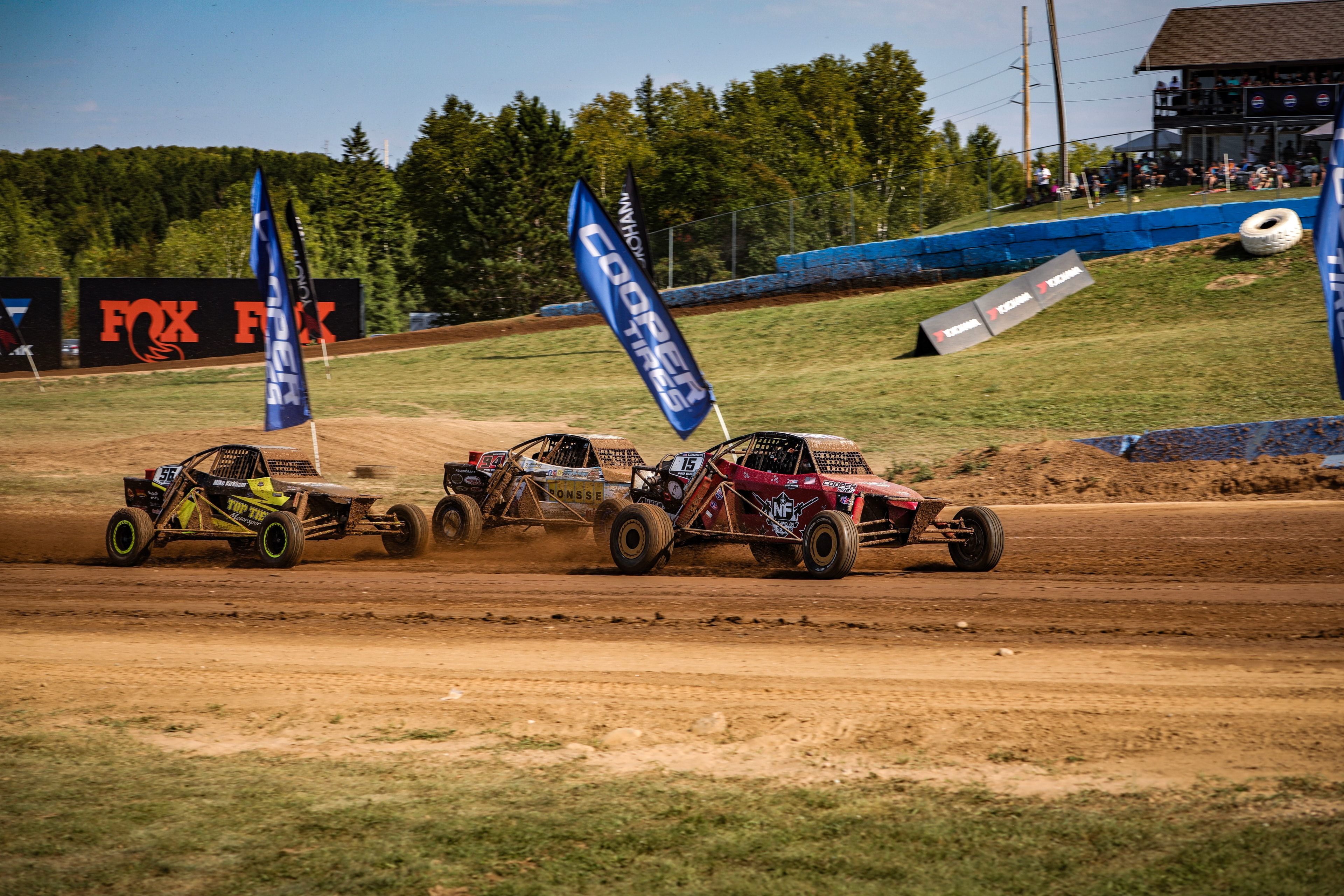Connor #15 Northwoods Firearms Pro Buggy leading a pack under Cooper Tires and Yokohama banners — Championship Off-Road Series, Crandon, WI