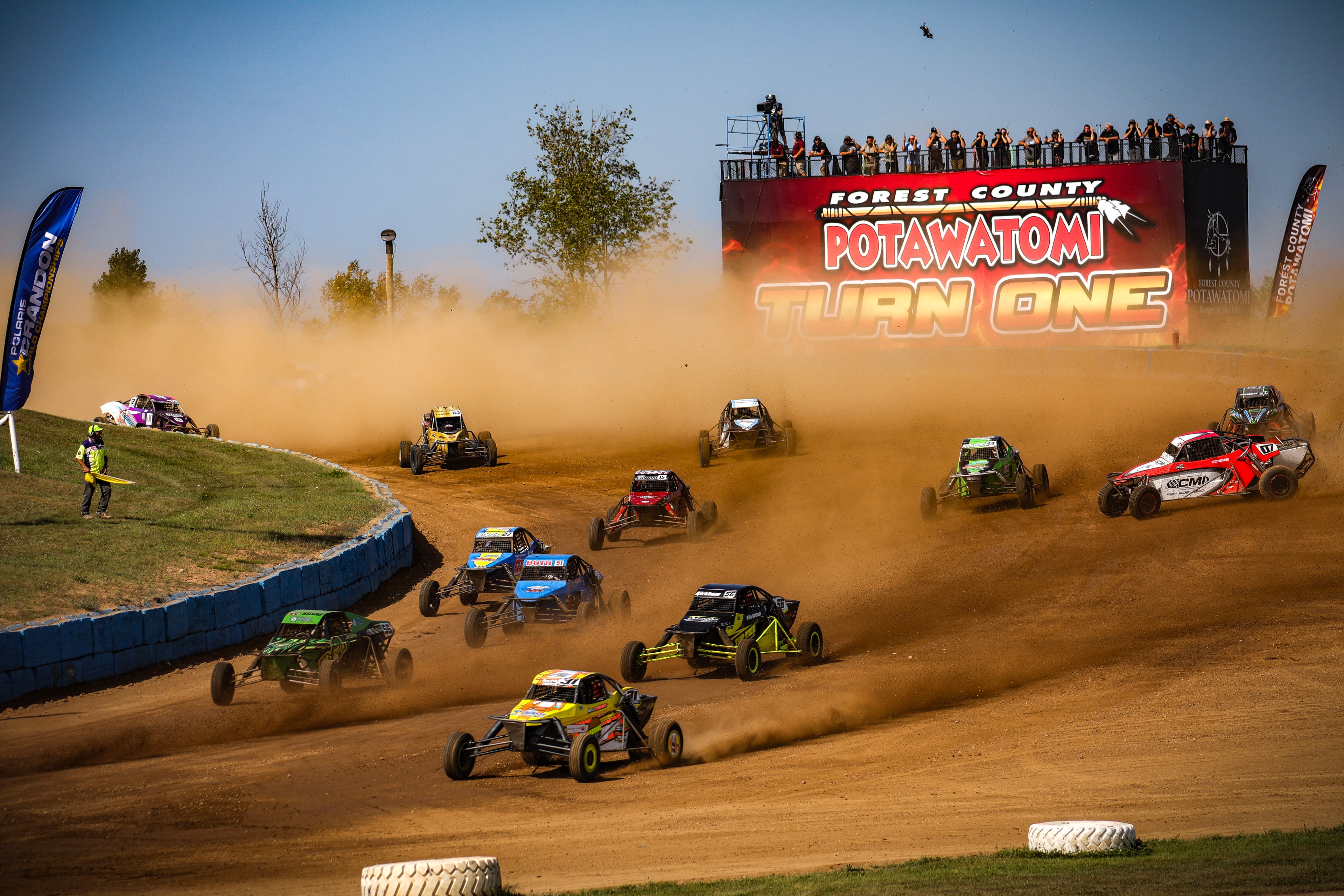 Full field of Pro Buggies charging through Forest County Potawatomi Turn One in a massive dust cloud — Championship Off-Road Series, Crandon, WI